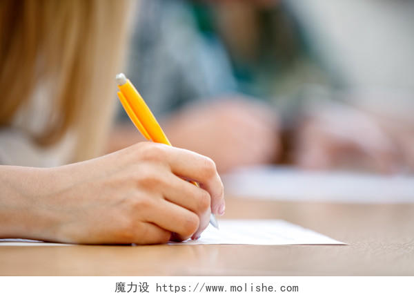 手握黄色钢笔正在白色纸张写字的人